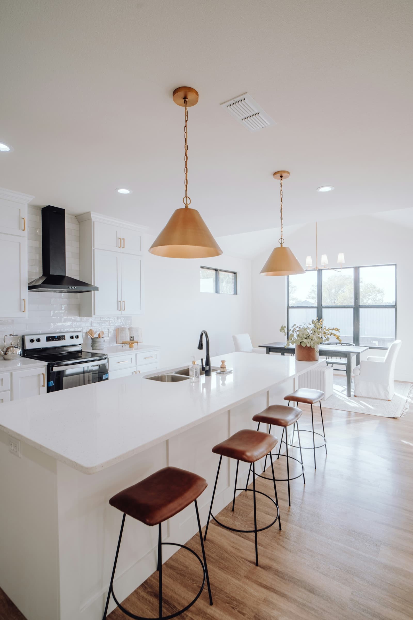 Bright open-plan kitchen with brass pendant lights and a white island